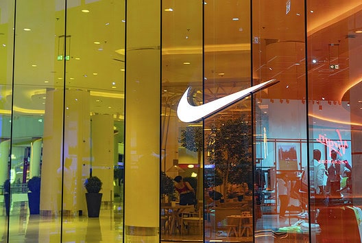 Nike logo on glass storefront in a shopping mall.