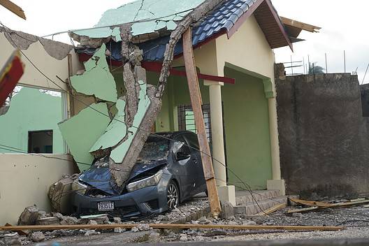 A car lies crushed under the debris of a collapsed building, showcasing the destructive force of Hurricane Melissa in Jamaica, Friday, 31 October 2025