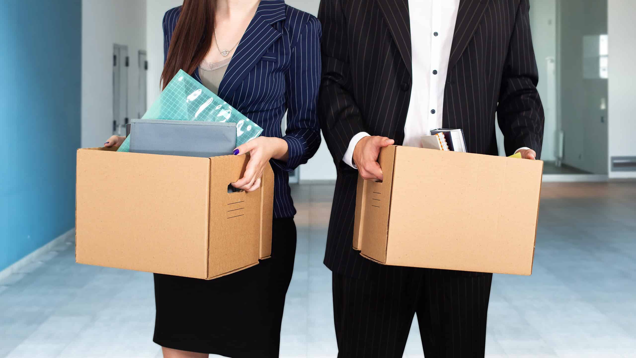 Unemployed managers with boxes in hands. Mass layoff of office staff concept. Fired man and woman in empty room. Problem of unemployment in society. Reduction of white collar workers