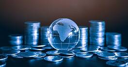 iles and Stack of money coin on black background with glass globe. Global business and financial concept background with blue color filter.