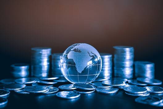 iles and Stack of money coin on black background with glass globe. Global business and financial concept background with blue color filter.