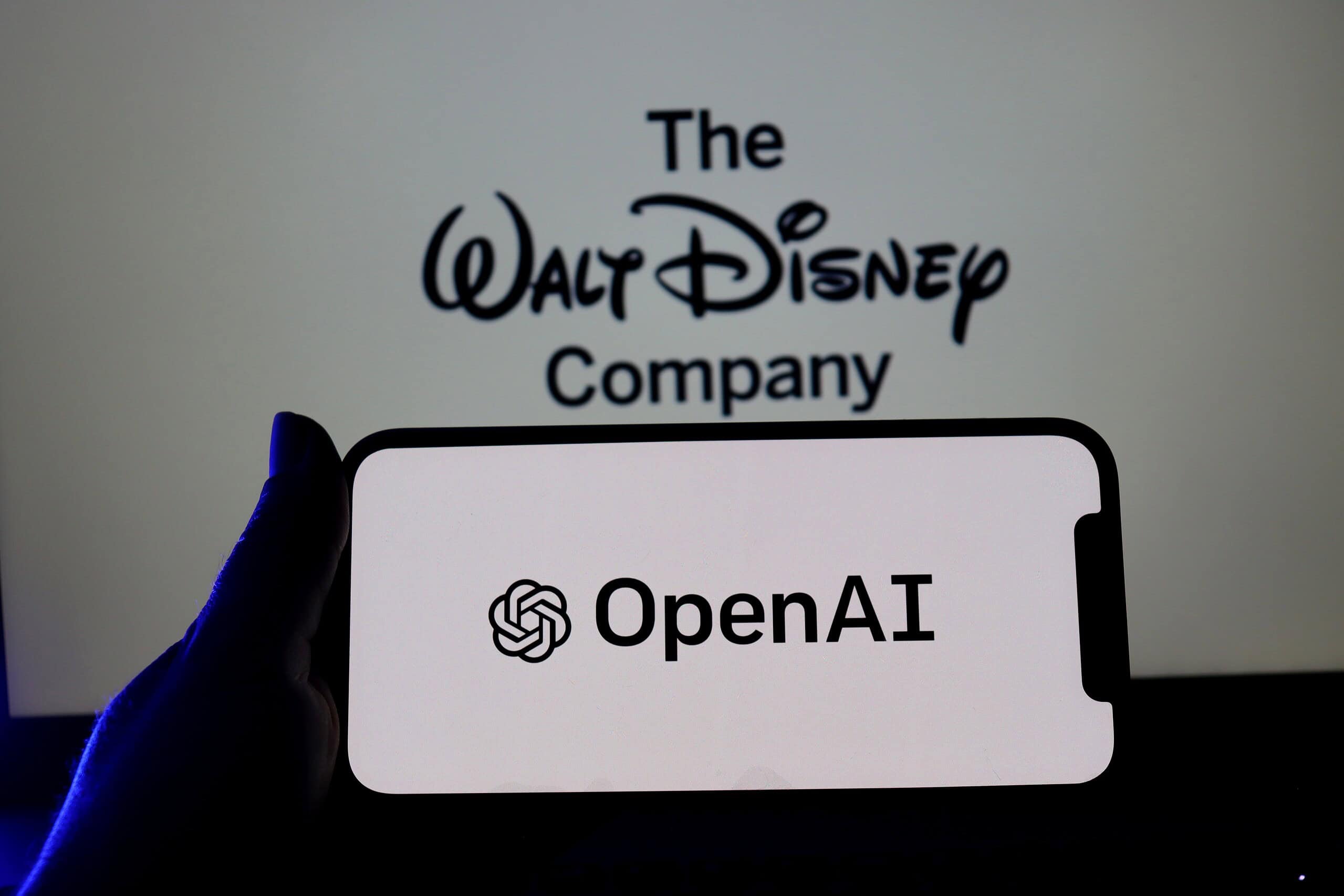 isney logo on smartphone screen with OpenAI logo in the background. The Walt Disney Company and Open AI.