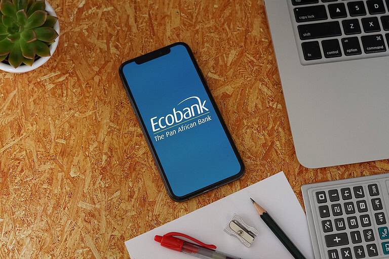 Ecobank Phone App with Stationery and Macbook. Ecobank is a pan-African banking conglomerate