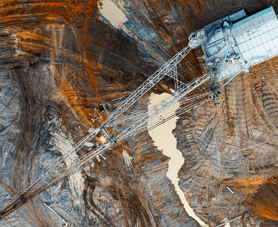 A large walking excavator works in a quarry for the extraction of rare metals. Drone view. Industrial landscape