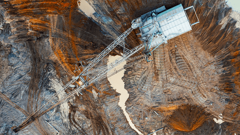 A large walking excavator works in a quarry for the extraction of rare metals. Drone view. Industrial landscape