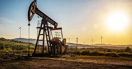 Working Oil pump and wind turbines at sunset. Industrial theme