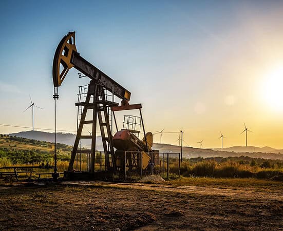 Working Oil pump and wind turbines at sunset. Industrial theme