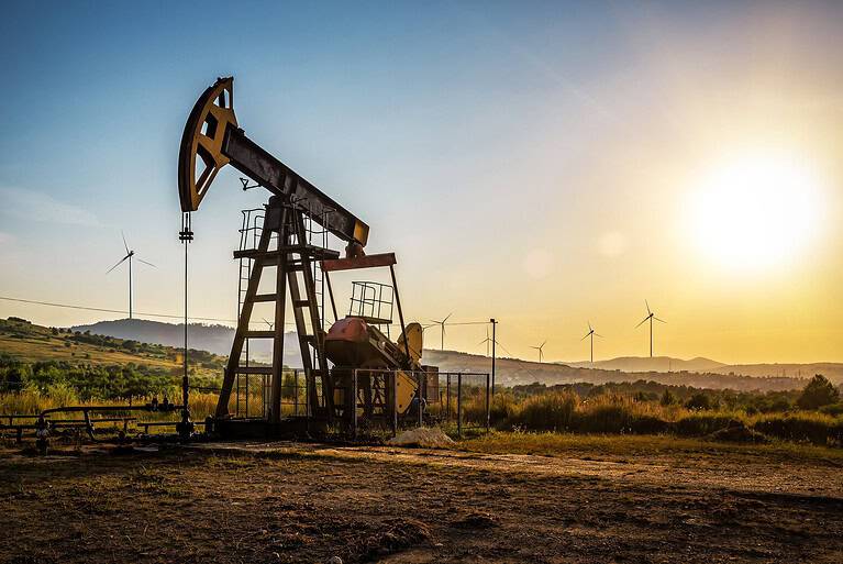 Working Oil pump and wind turbines at sunset. Industrial theme
