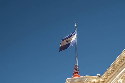 Isolated El Salvador flag waving against blue sky in San Salvador historical center. Independence, sovereignty, state government concept.