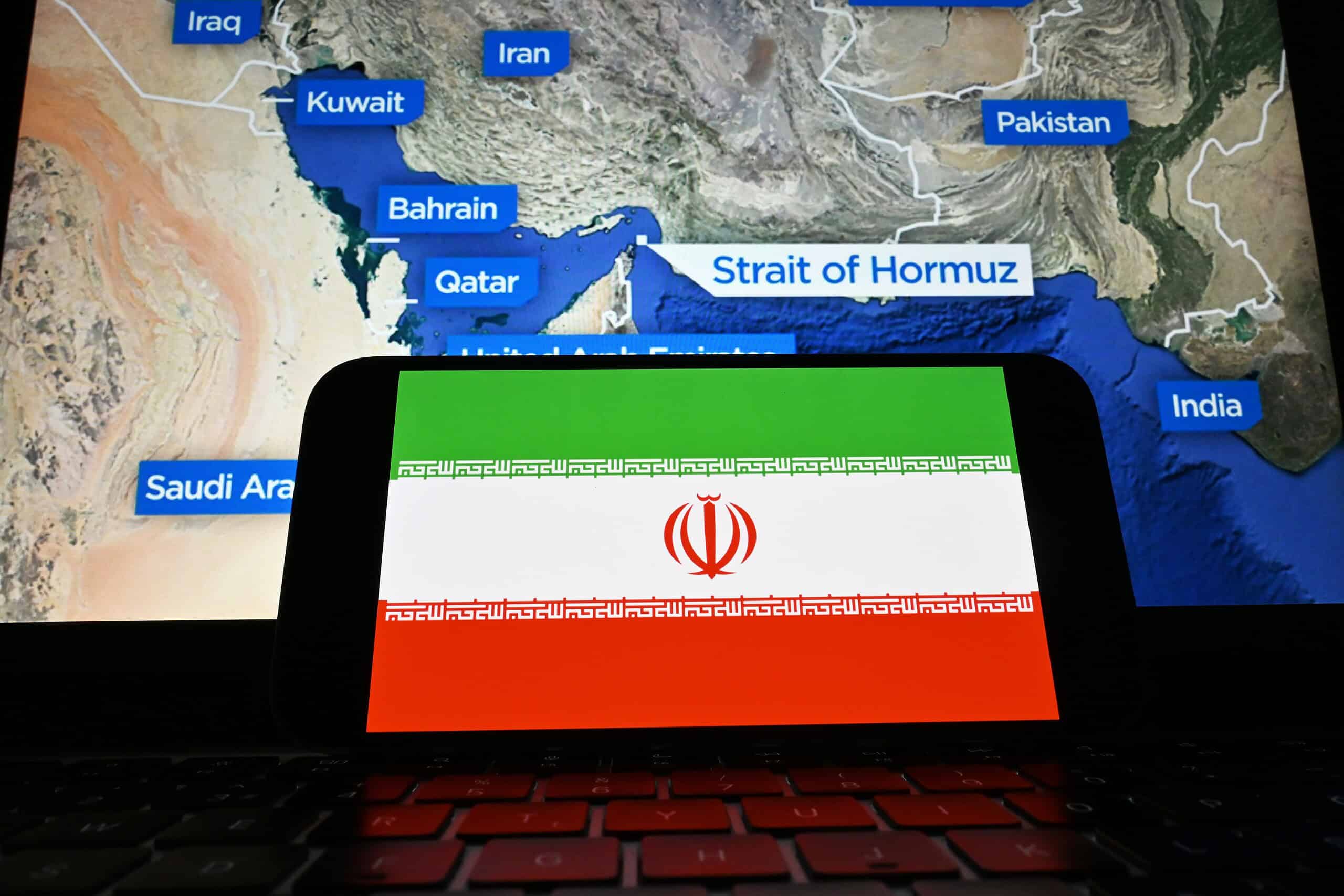 The Iranian flag is visible on the screen. After U.S. attacks, Iran decided to close the Strait of Hormuz.
