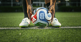 Soccer ball positioned on a green field, ready for play, with a focus on sports finance and global s.