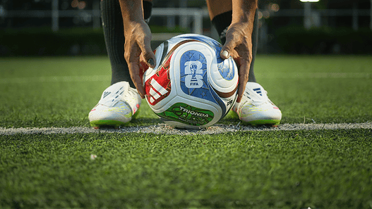Soccer ball positioned on a green field, ready for play, with a focus on sports finance and global s.