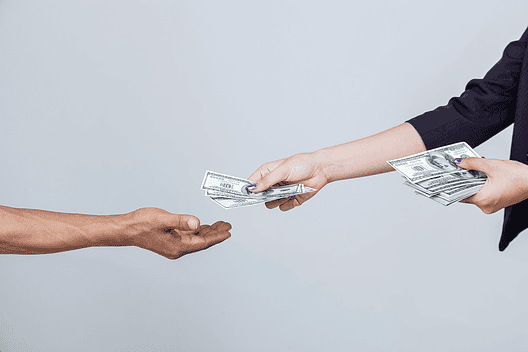 two arms stretched out handing cash to one hand