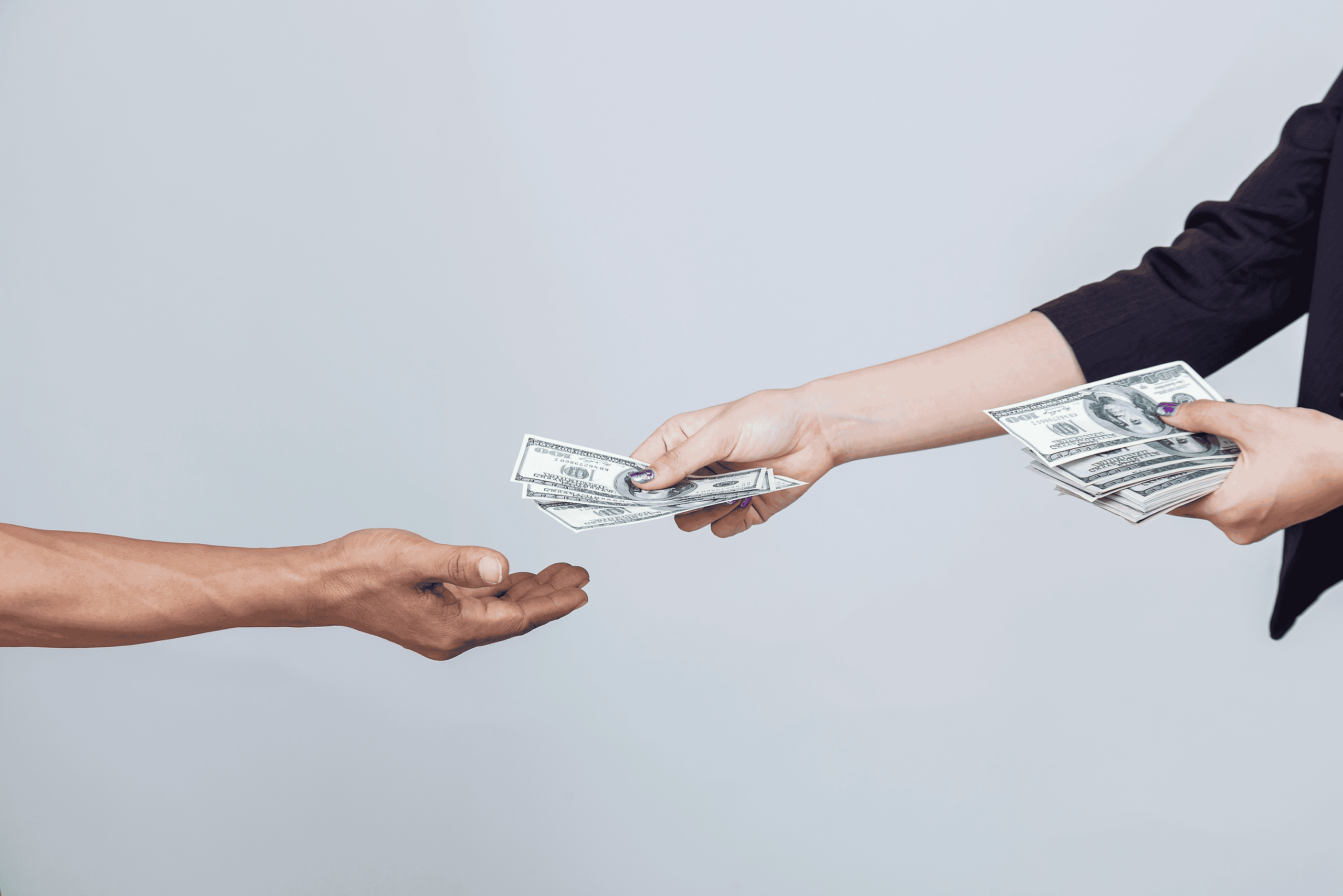 two arms stretched out handing cash to one hand