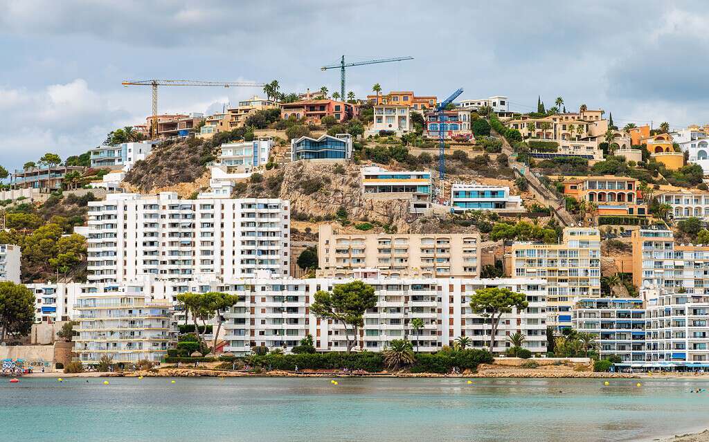 Modern hillside homes with construction cranes overlooking the waterfront.