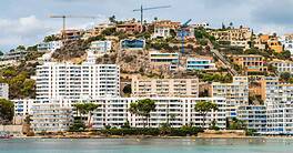 Modern hillside homes with construction cranes overlooking the waterfront.