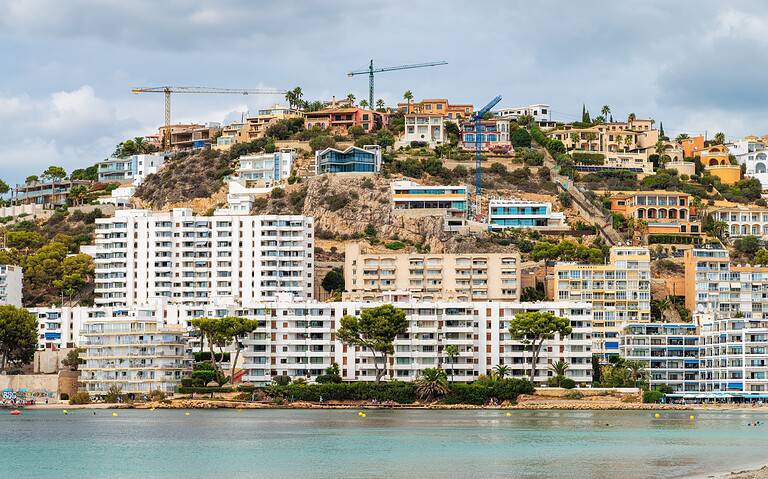 Modern hillside homes with construction cranes overlooking the waterfront.