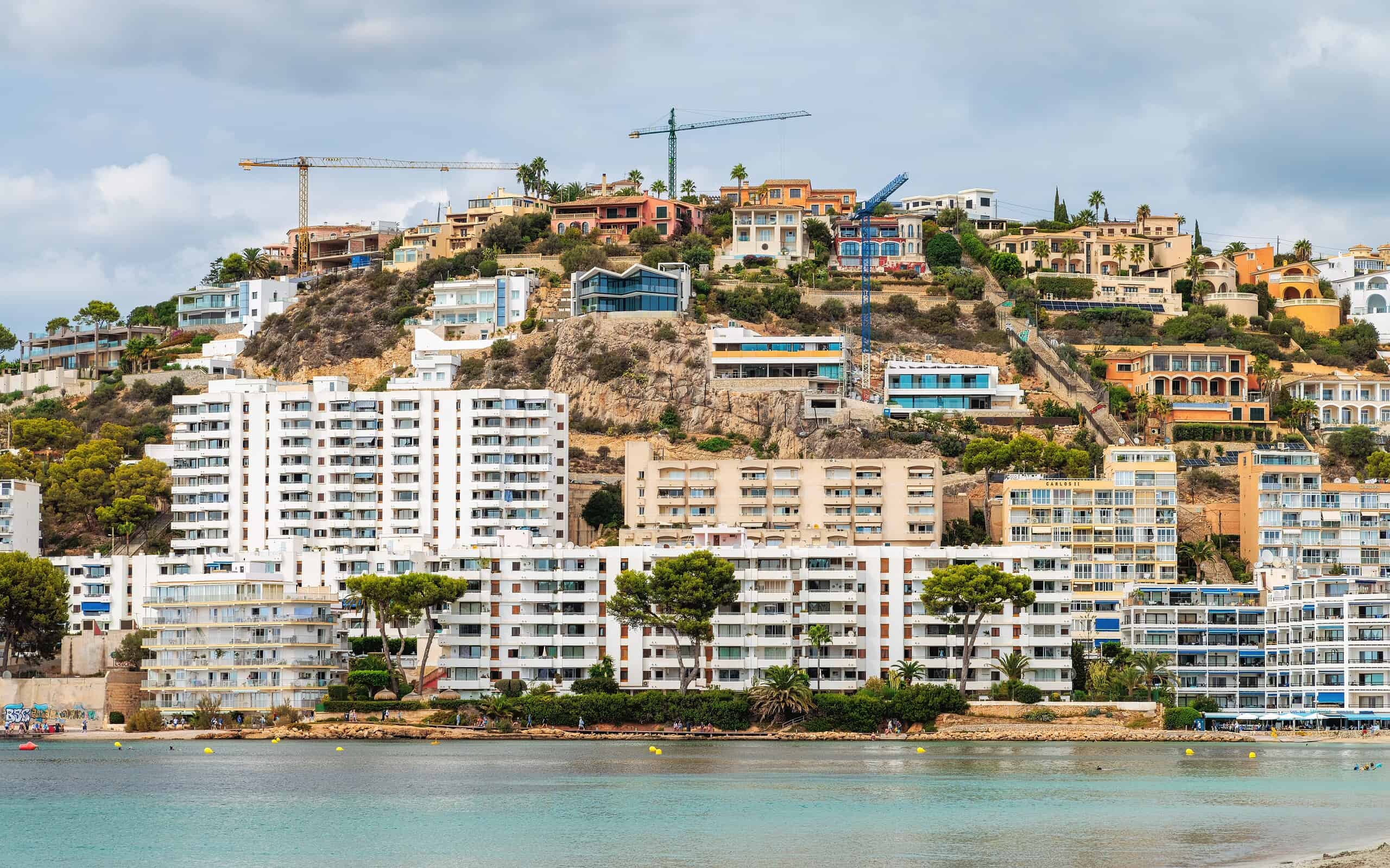 Modern hillside homes with construction cranes overlooking the waterfront.