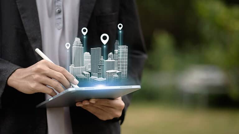 A person uses a tablet to project a holographic 3D model of a smart city with location markers. Concept of urban planning, real estate technology, architecture, and navigation.