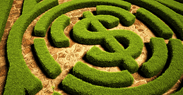 Maze with dollar sign made of green bushes on stone pathway.