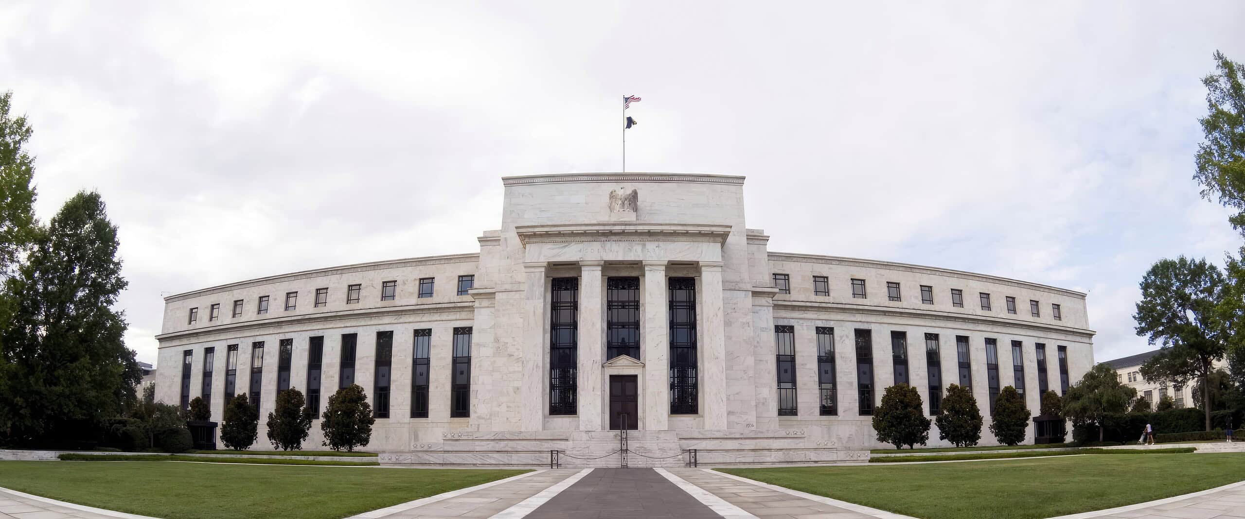 Federal Reserve building with a flag on top and surrounding trees.