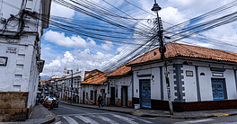 Typical street with white walls colonial architecture and a web of electrical wires creating contrast between the past and present in the city in Sucre, Bolivia