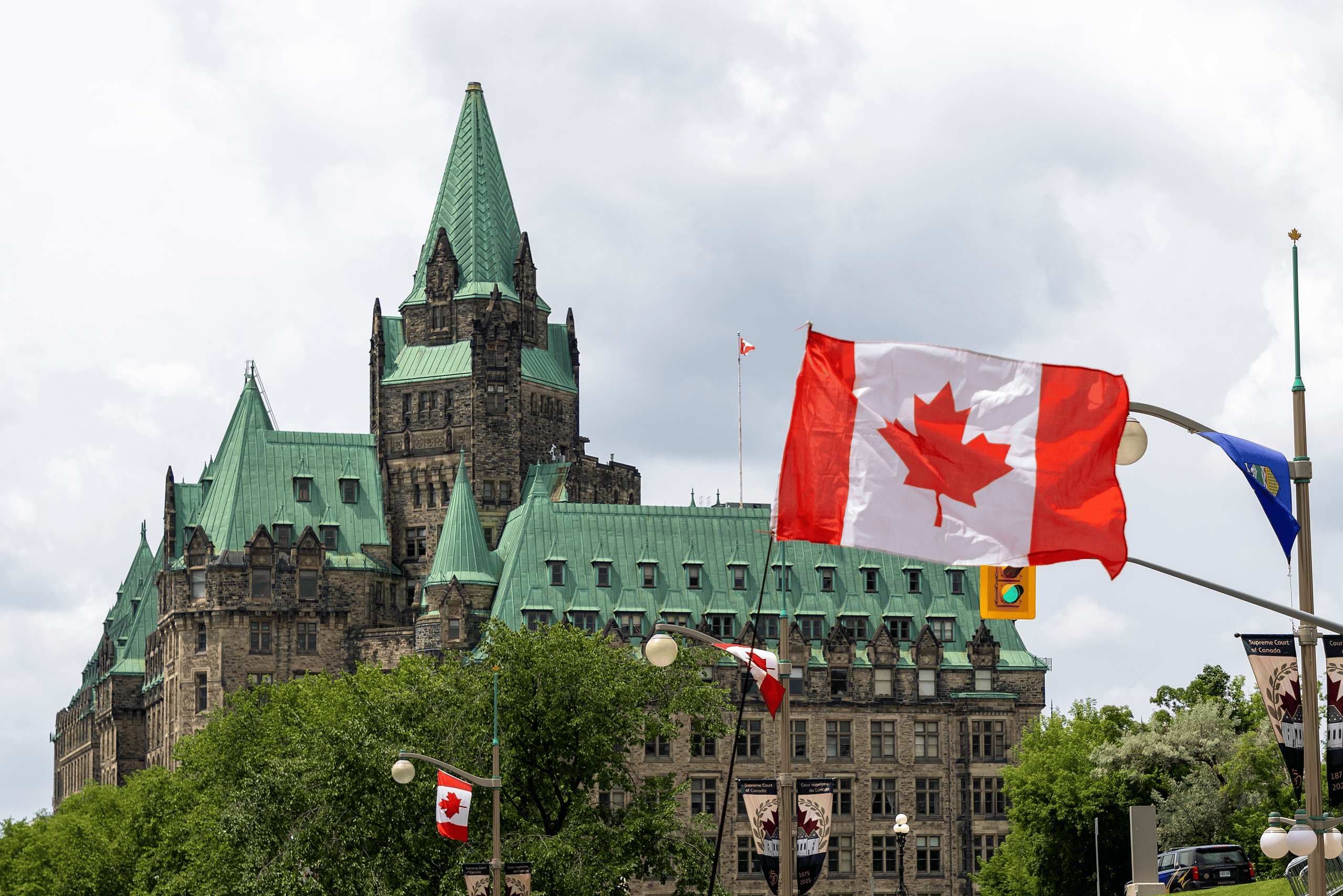 Ottawa Parliament Hill with Canadian flags and historic architecture.