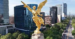 Golden angel statue overlooking Mexico City skyline and green parks.