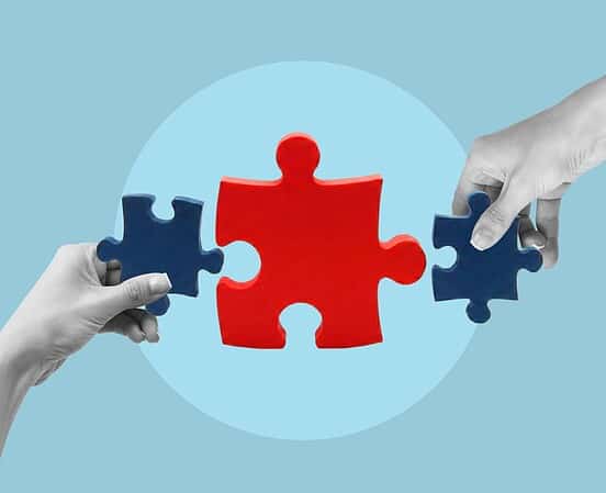 Two hands holding puzzle pieces fitting together for finance.