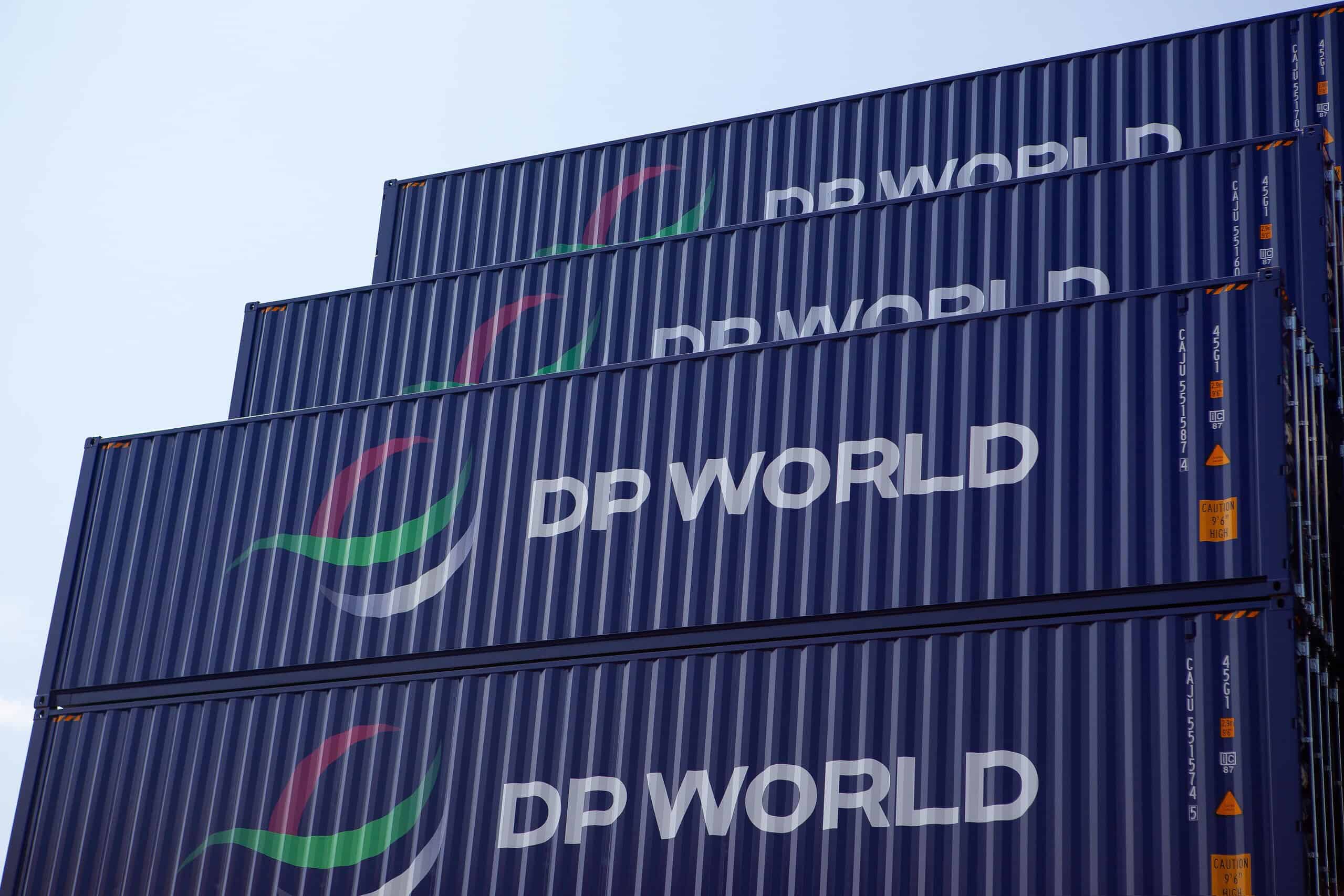 Global Logistics and Supply Chain Concept with Stacked dark blue containers for marine shipping of DP World logistics, with its logs DP WORLD clearly painted in white on the dark blue coating of the containers against blue sky in a container yard