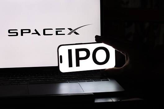 SpaceX IPO announcement displayed on a smartphone in front of a laptop.