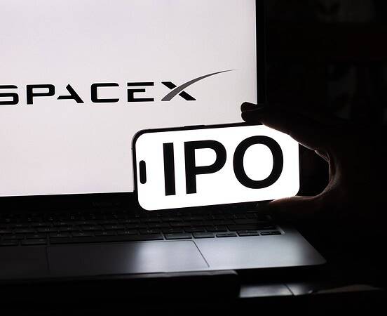 SpaceX IPO announcement displayed on a smartphone in front of a laptop.