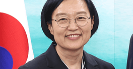Han Seong-sook smiling, South Korean flag in background.