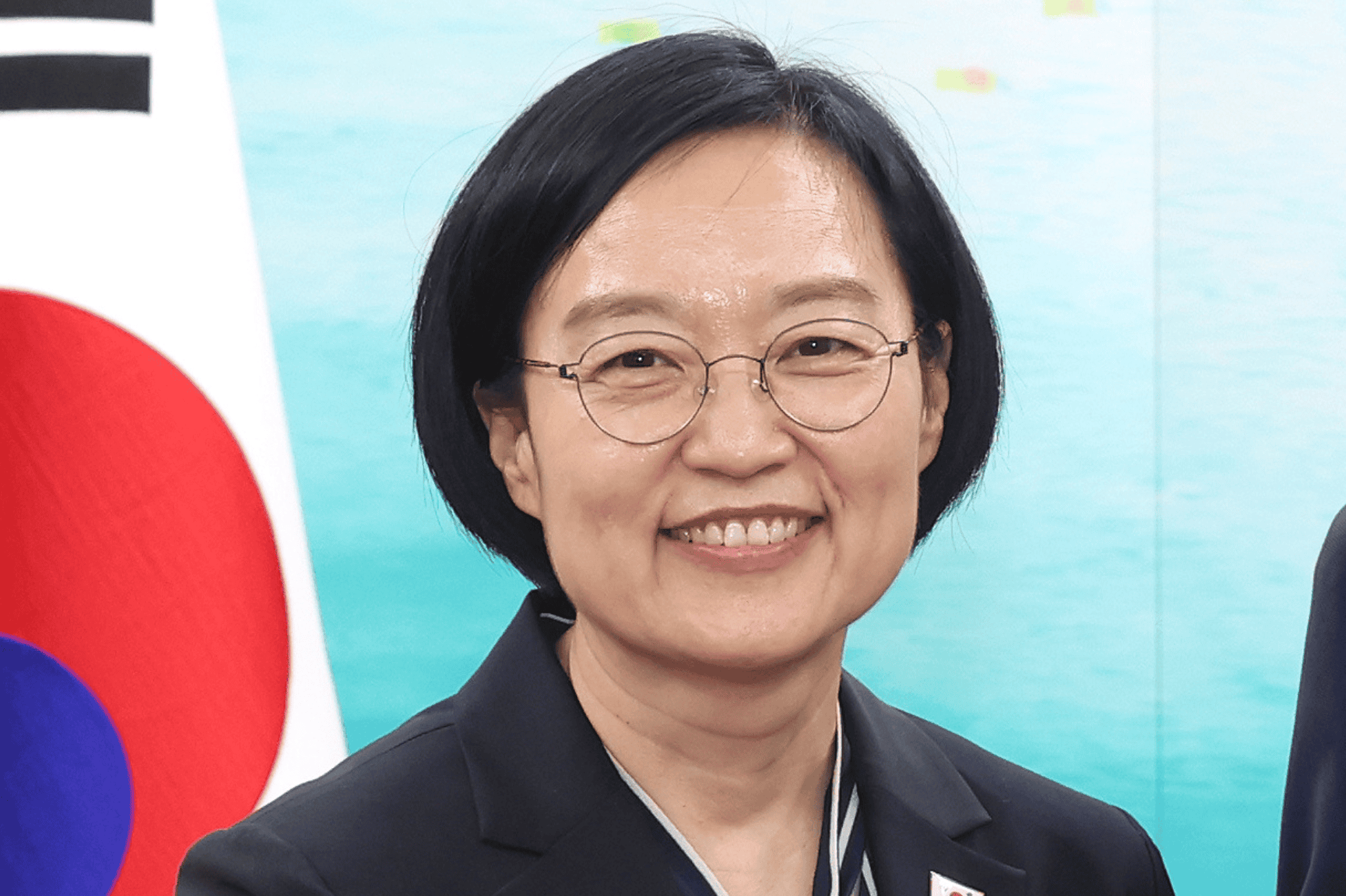 Han Seong-sook smiling, South Korean flag in background.