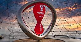 Qatar 2022 FIFA World Cup trophy inside a geodesic dome at sunset.