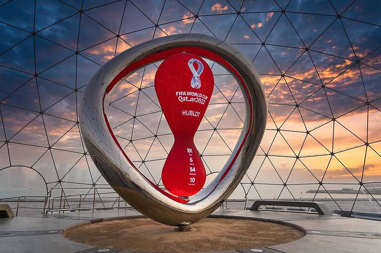 Qatar 2022 FIFA World Cup trophy inside a geodesic dome at sunset.