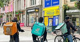 Group of takeaway food delivery riders waiting for their next order in a street in Cardiff city centre