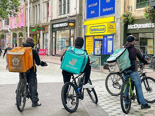 Group of takeaway food delivery riders waiting for their next order in a street in Cardiff city centre