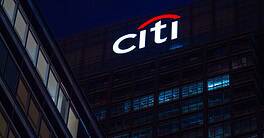 Citi logo illuminated on office building at night.
