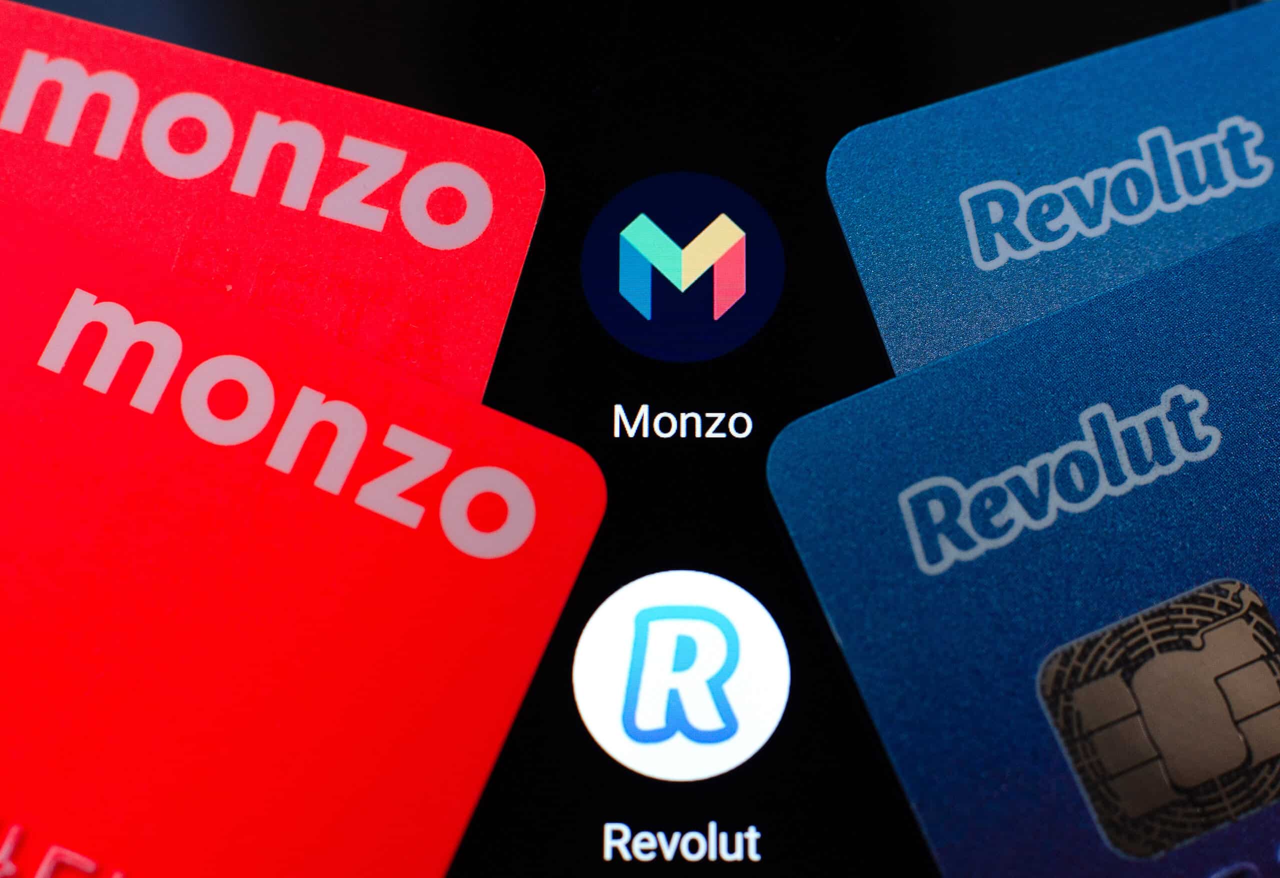Revolut and Monzo fintech cards with logos on black background.