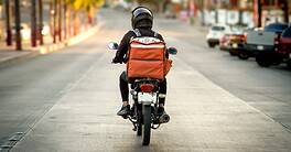 Motorcycle rider with backpack on city street during daytime.