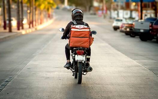 Motorcycle rider with backpack on city street during daytime.