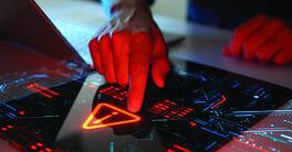 Man interacting with a holographic touchscreen interface in red color. Concept of cyber attack, malware, data breach, system hacking, virus, spyware, compromised information and urgent attention.