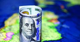 Rolled up one hundred dollar bill on top of a South America map
