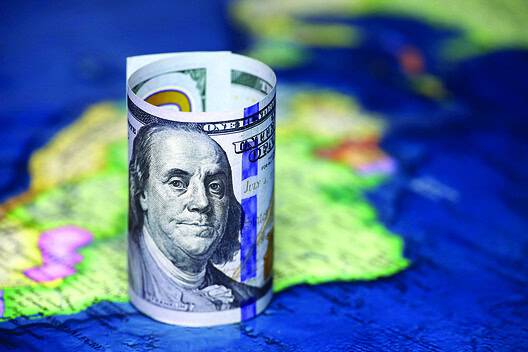 Rolled up one hundred dollar bill on top of a South America map