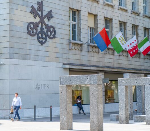 UBS sign on the street wall of UBS office building with flags entrance. AG Swiss global financial services company. UBS Bank Headquarters with Swiss Canton Flag. Zurich, Switzerland - June 2026