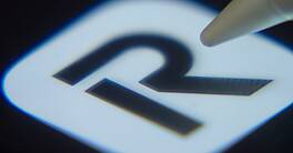 Close-up of the Revolut app icon on a smartphone screen with a stylus.