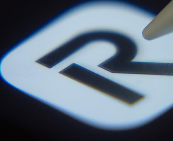 Close-up of the Revolut app icon on a smartphone screen with a stylus.