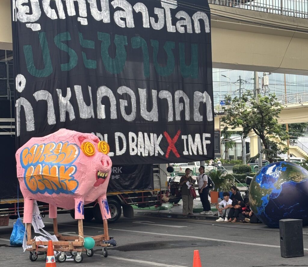 A papier-mâché pig with gold coin eyes stands on the street during demonstrations outside the IMF annual meetings in Bangkok.